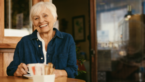 A smiling elder lady drinking coffee 