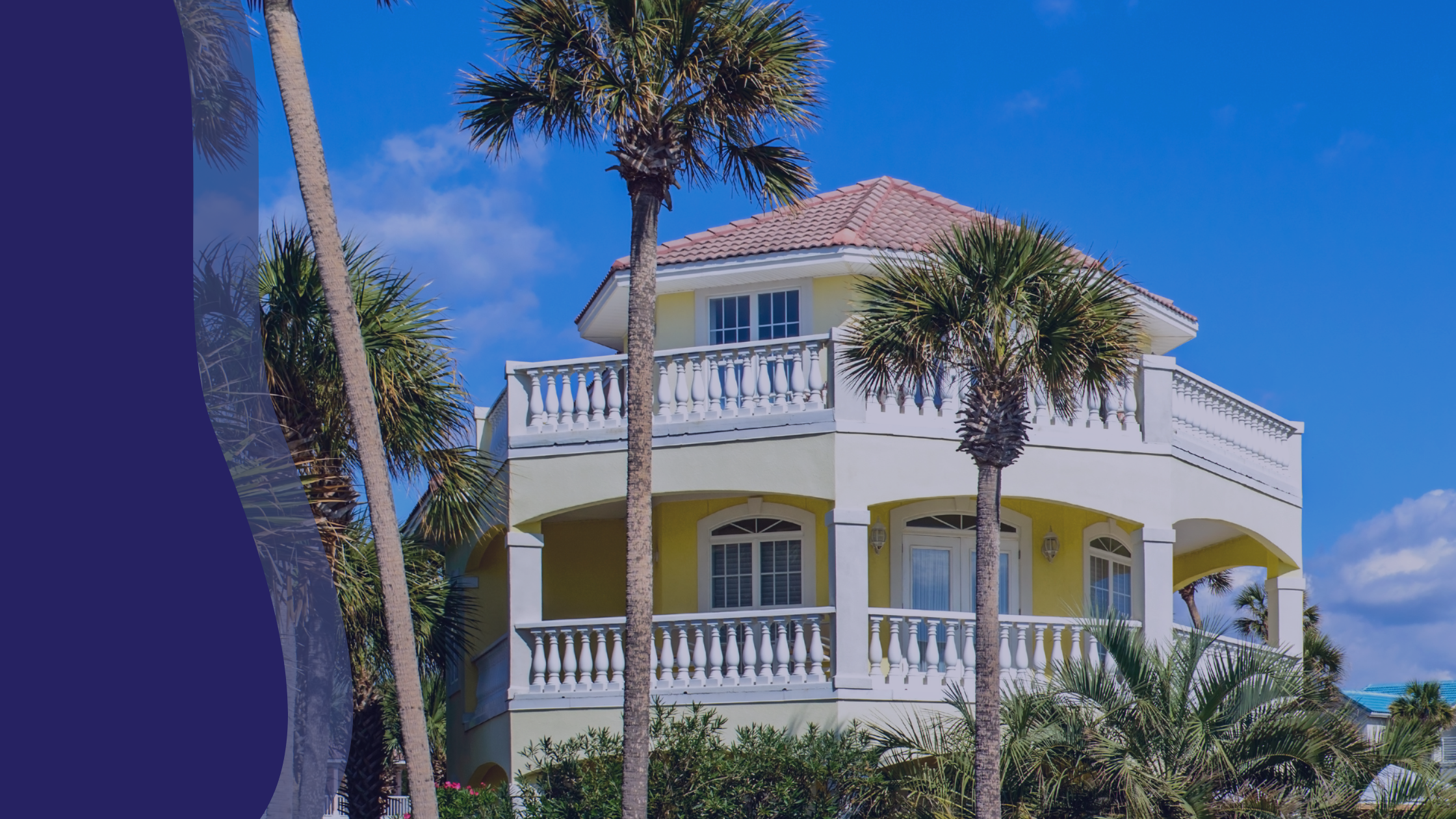 yellow vacation home with palm trees in foreground against a blue sky